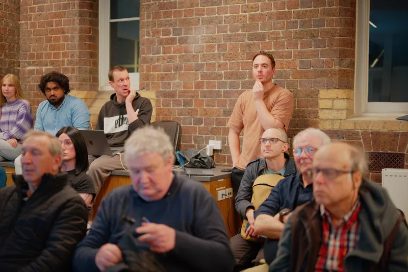 Gallery image: 02 listening 06 june the room watching a talk.webp